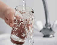 Osoba z objawami cukrzycy nalewa wodę z kranu do szklanki